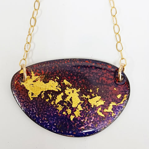 Oval shaped pendant with layers of enamel colours in burgundy, red and purple with 22ct gold leaf particles decorating the middle of the shape. Gold plated chain with round links is attached to either side with gold plated jump rings.