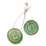 Women's suffrage reversible drop earrings showing the green sides. The earrings are made from disks with a printed end of scroll motif in silvery colour. The silver earring hoops are an eliptical shape and  each earring wire goes through a central hole in the disk.