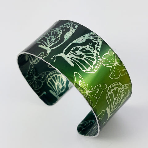 Anodized aluminum cuff printed with butterflies and dyed a dark green and lighter green