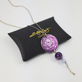 Round, purple, aluminium pendant with printed rose pattern on a sterling silver chain with a purple amethyst bead and a smaller agate bead bead