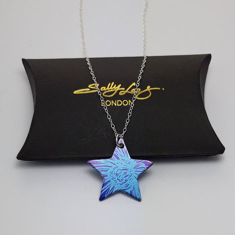 Star pendant on a sterling silver chain displayed on a black gift box. This star pendant is printed with a section of a chrysanthemum flower in blue with a purple background.