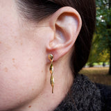 Close up on the ear of gold-plated silver twist earrings with an etched roses pattern. Hand crafted by Sally Lees (London).