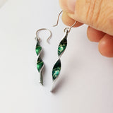 Green aluminium twist earrings with a lily of the valley flower print on both sides and with silvery coloured edges.