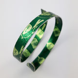 Green, anodised, aluminium cuff printed with small birds on the outside and bird cages on the inside. Called 'The bird has flown' 