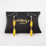 Yellow daffodil earrings displayed on a black pillow shaped box with the sally lees logo in gold