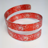 Anodized aluminum wrap around cuff in citrus orange with silvery coloured printed floral pattern