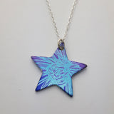 Star pendant on a sterling silver chain. This star pendant is printed with a section of a chrysanthemum flower in blue with a purple background.