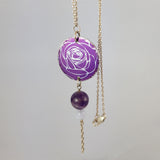 Round, purple, aluminium pendant with printed rose pattern on a sterling silver chain with a purple amethyst bead and a smaler agate bead bead