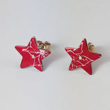 Red star poinsettia stud earrings for December birthdays displayed on o