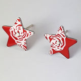 Front of two aluminium stud earrings in the shape of stars with an abstracted linear pattern of roses on each star in a silver colour. The pattern features on the side of each stud.