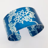 Hand made anodised aluminium cuff decorated with large prints of carnations. and dyed teal.