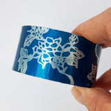 Hand made anodised aluminium cuff decorated with large prints of carnations. and dyed teal.