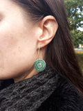 Women's suffrage earrings showing the green disk of these reversible drop earrings. Showing the earring worn on a model .